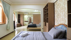 Une chambre d’hôtel comprenant un lit, une armoire, un miroir et une salle de bain visible à travers une arche.