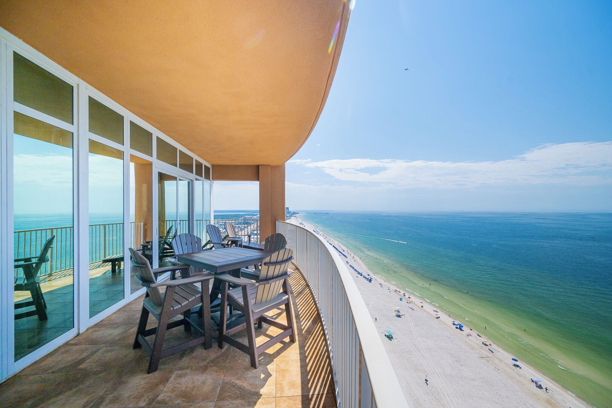 A balcony with a table and chairs overlooking a beach.