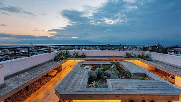 A rooftop terrace with a wooden deck, seating areas, and a view of the cityscape. - Floral Holiday Guesthouse (Dali)