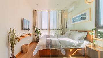 Un dormitorio moderno con una cama grande, un televisor montado en la pared y un ventanal con cortinas.