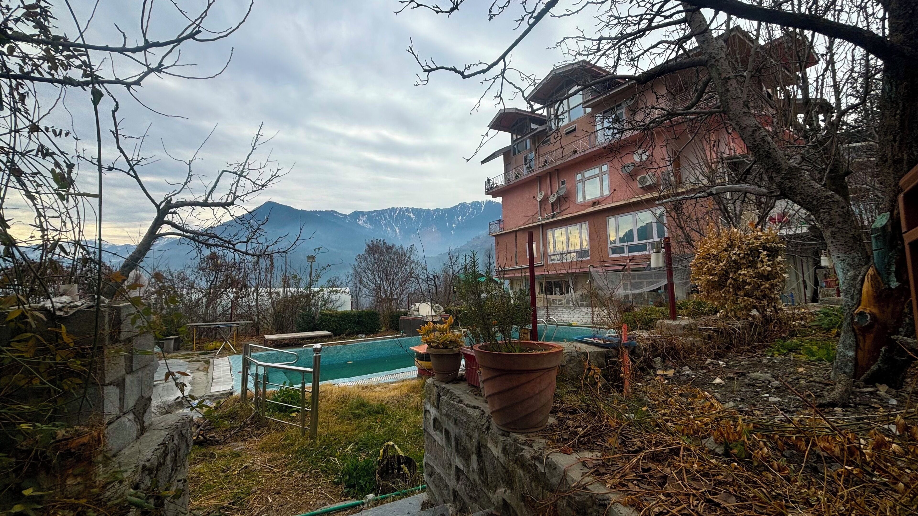 A residential building with a pool, surrounded by mountains and trees.