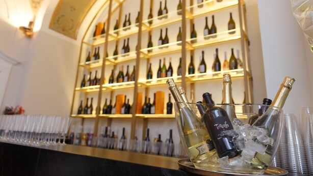 Una zona de bar con estantes llenos de botellas de vino y una bandeja con botellas de champán y hielo.