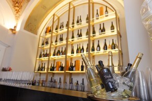 Angolo bar con scaffali di bottiglie di vino e un vassoio con bottiglie di champagne e ghiaccio.