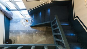 Una escalera moderna con barandilla de metal, tragaluz y una lámpara de pared de diseño único.