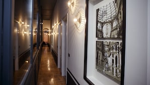 Un pasillo con obras de arte enmarcadas, piso de madera y luminarias modernas.