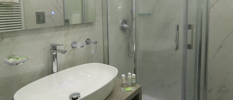 A modern bathroom with a glass-enclosed shower, a white sink, and a mirror above it.