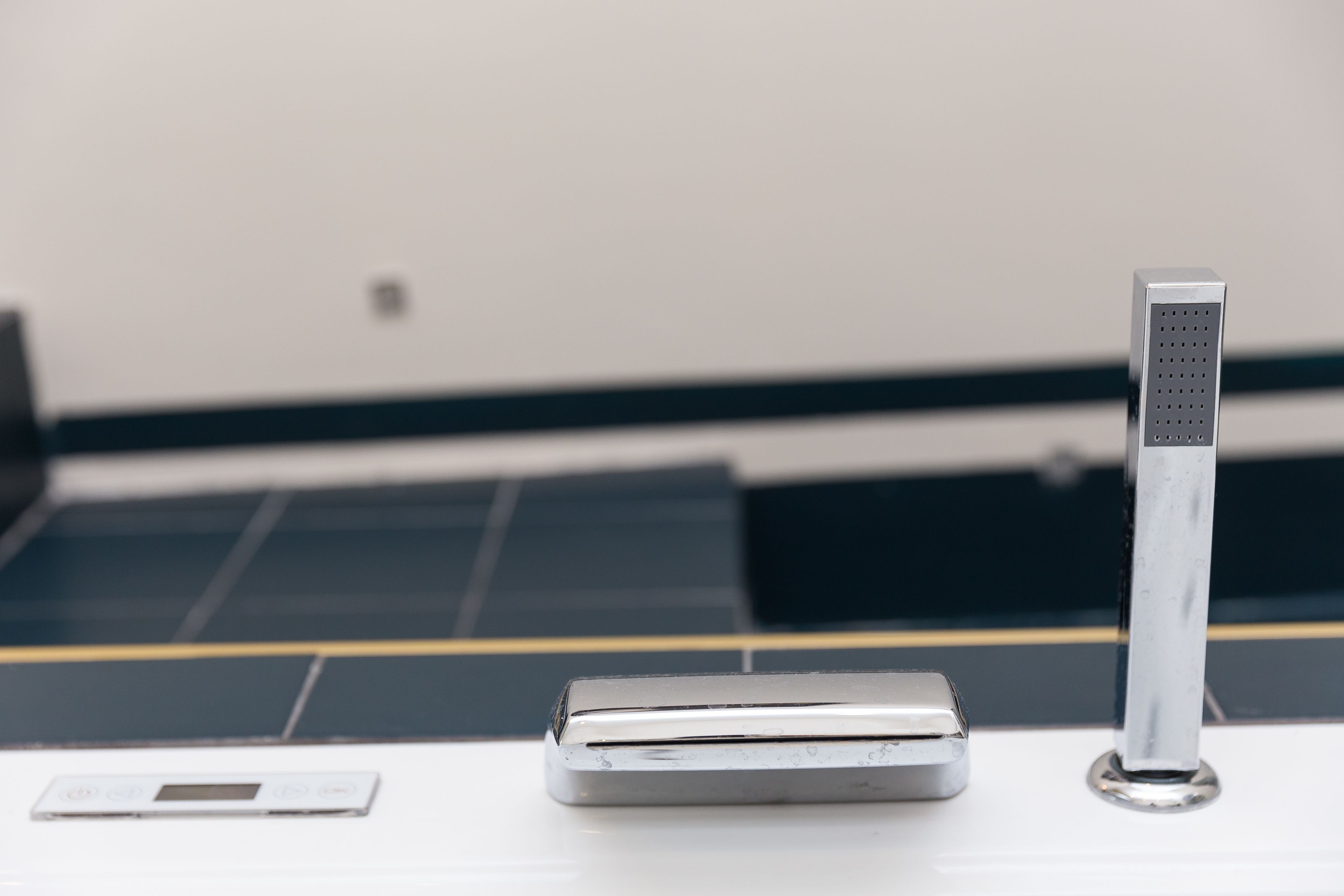 A metallic object with a rectangular shape and a perforated section on one side, placed on a flat surface.