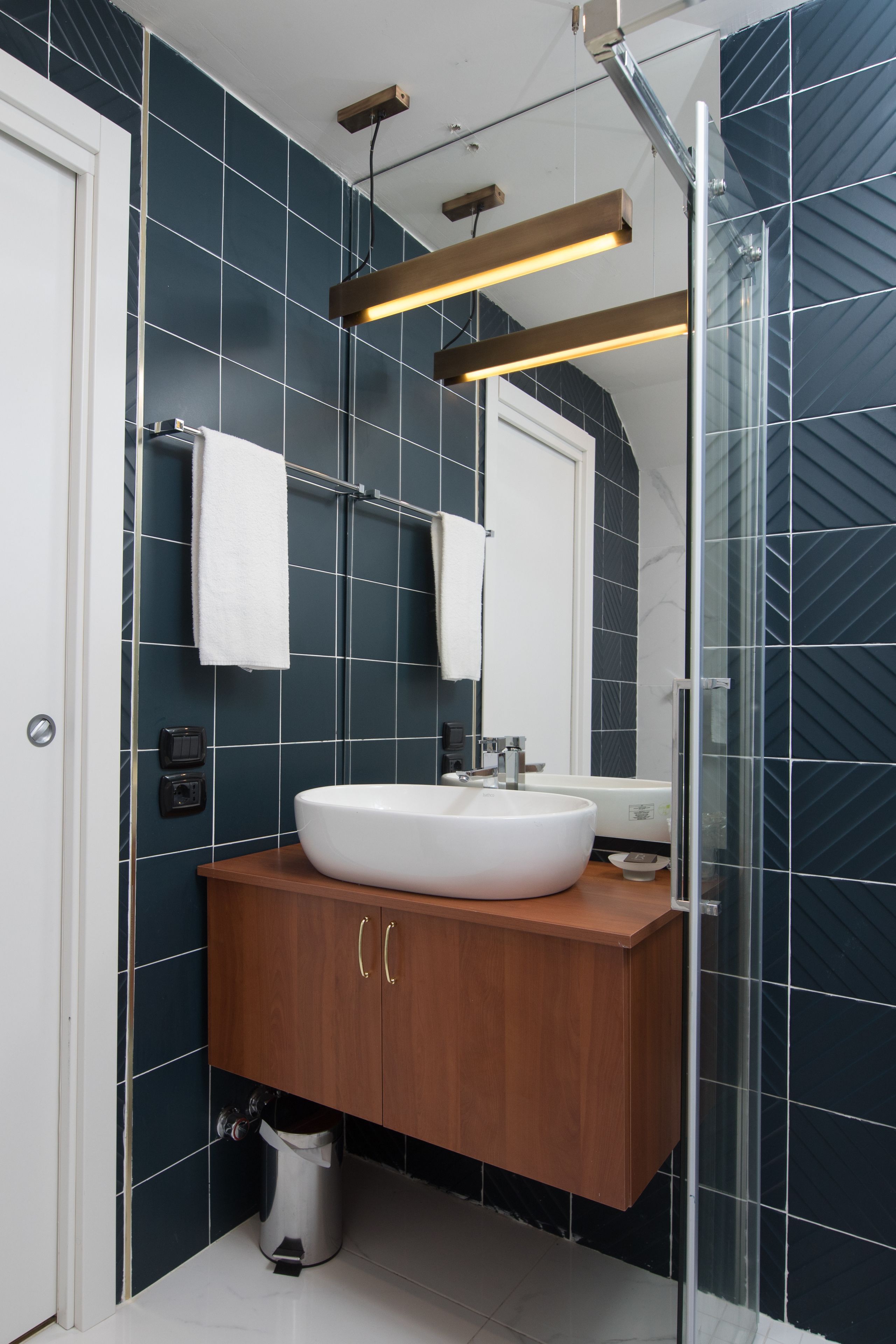 Une salle de bain moderne avec un lavabo blanc, un meuble-lavabo en bois et une cabine de douche en verre.