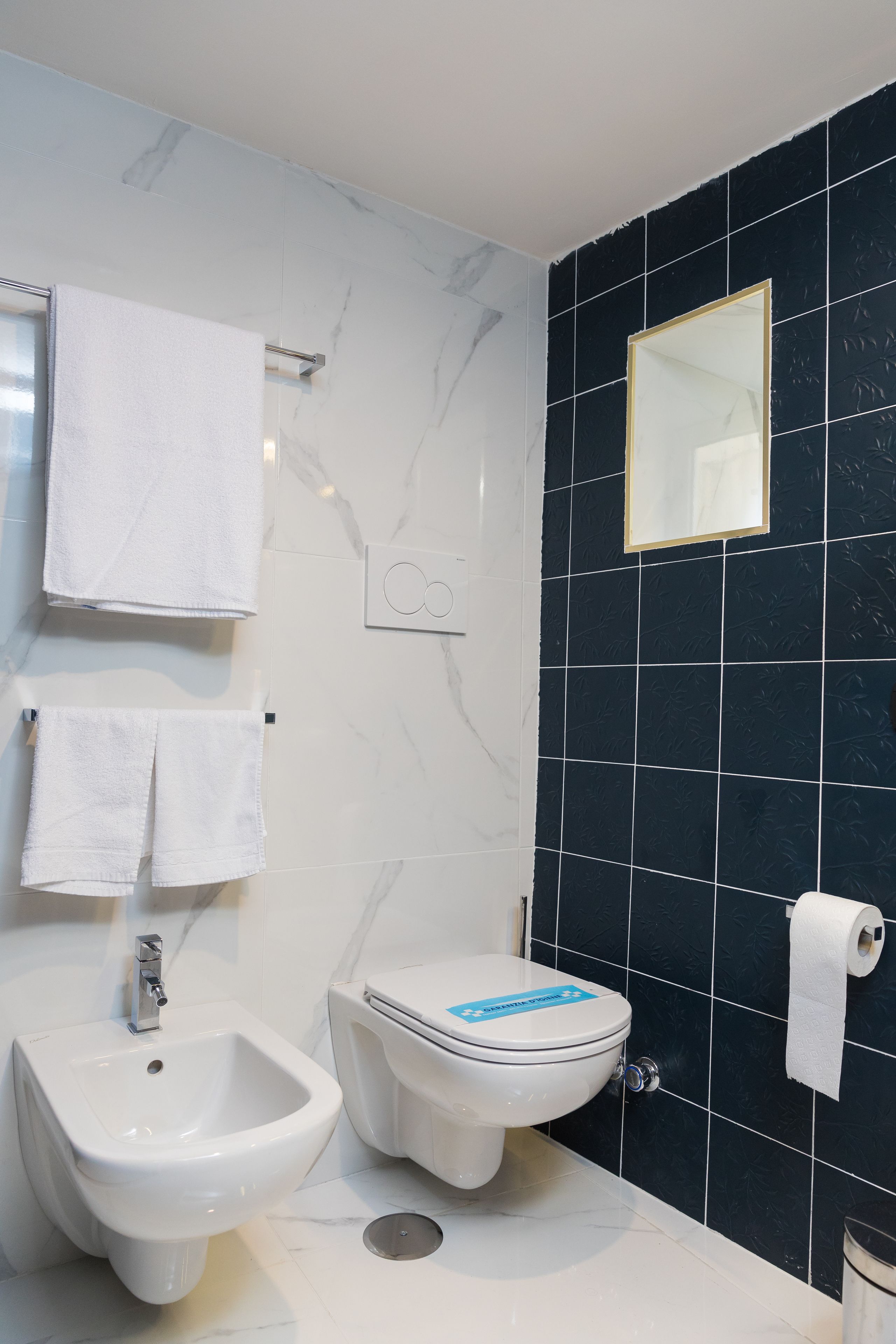 Une salle de bain équipée d’un bidet, de toilettes et d’un miroir.