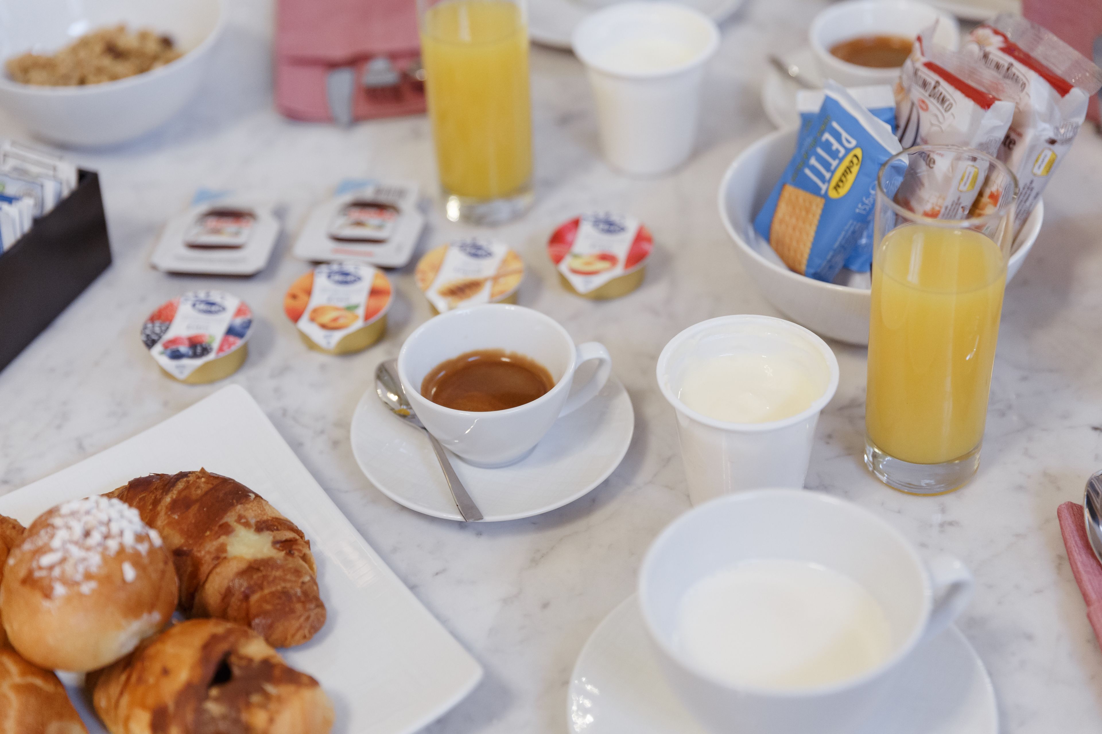 Una tavola imbandita per la colazione con dolci, caffè, succo e snack confezionati.