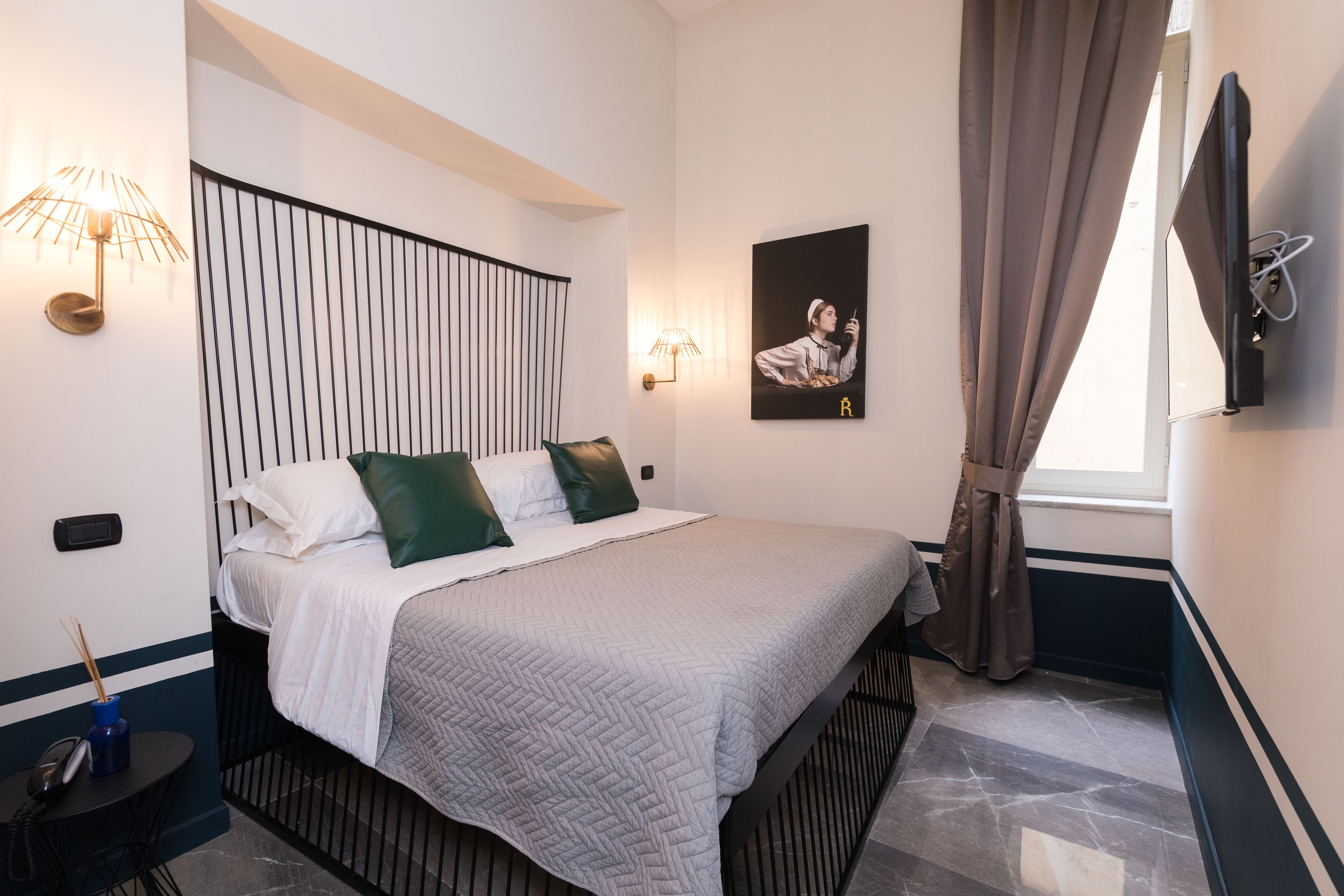 Habitación de hotel moderna con cama, escritorio, lámpara, un cuadro en la pared y ventana con cortinas.