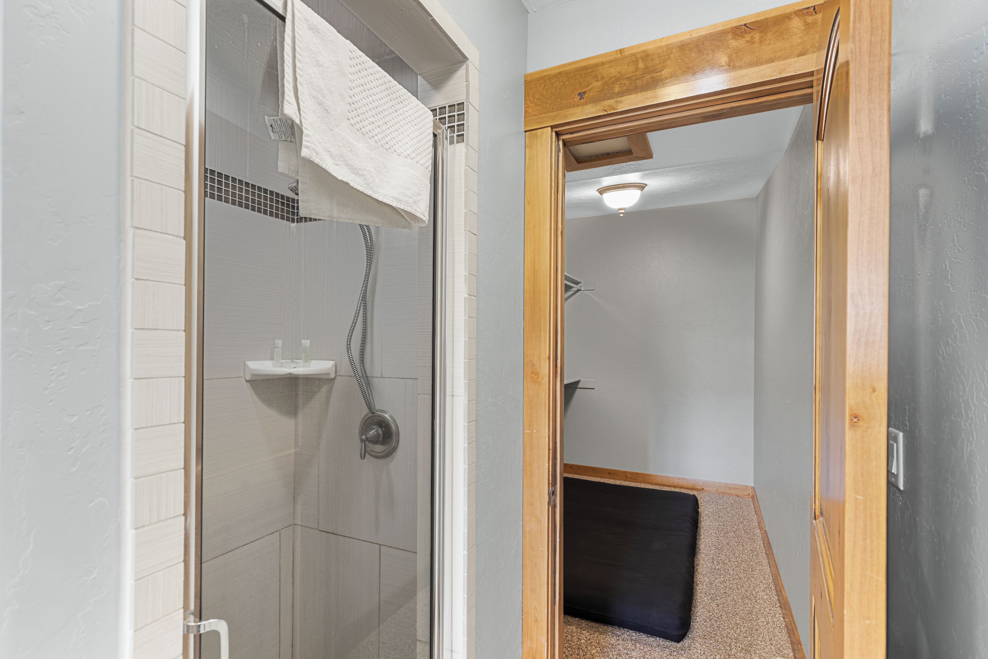 A modern bathroom with a glass shower enclosure, a wooden door frame, and a visible towel rack.