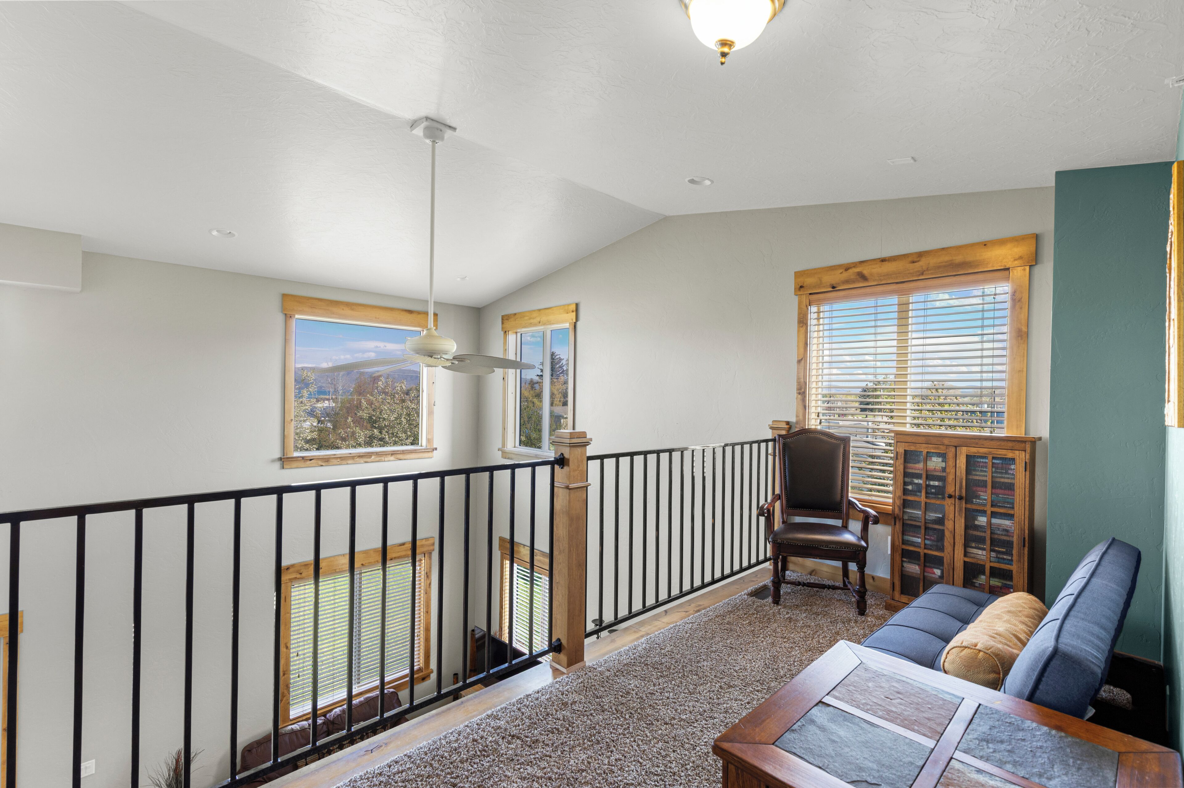 A balcony with a view, a chair, a sofa, and a wooden cabinet.