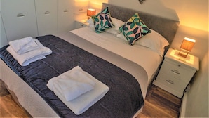 Una camera d'albergo con un letto grande, due comodini e una decorazione a forma di cuore appesa al muro.