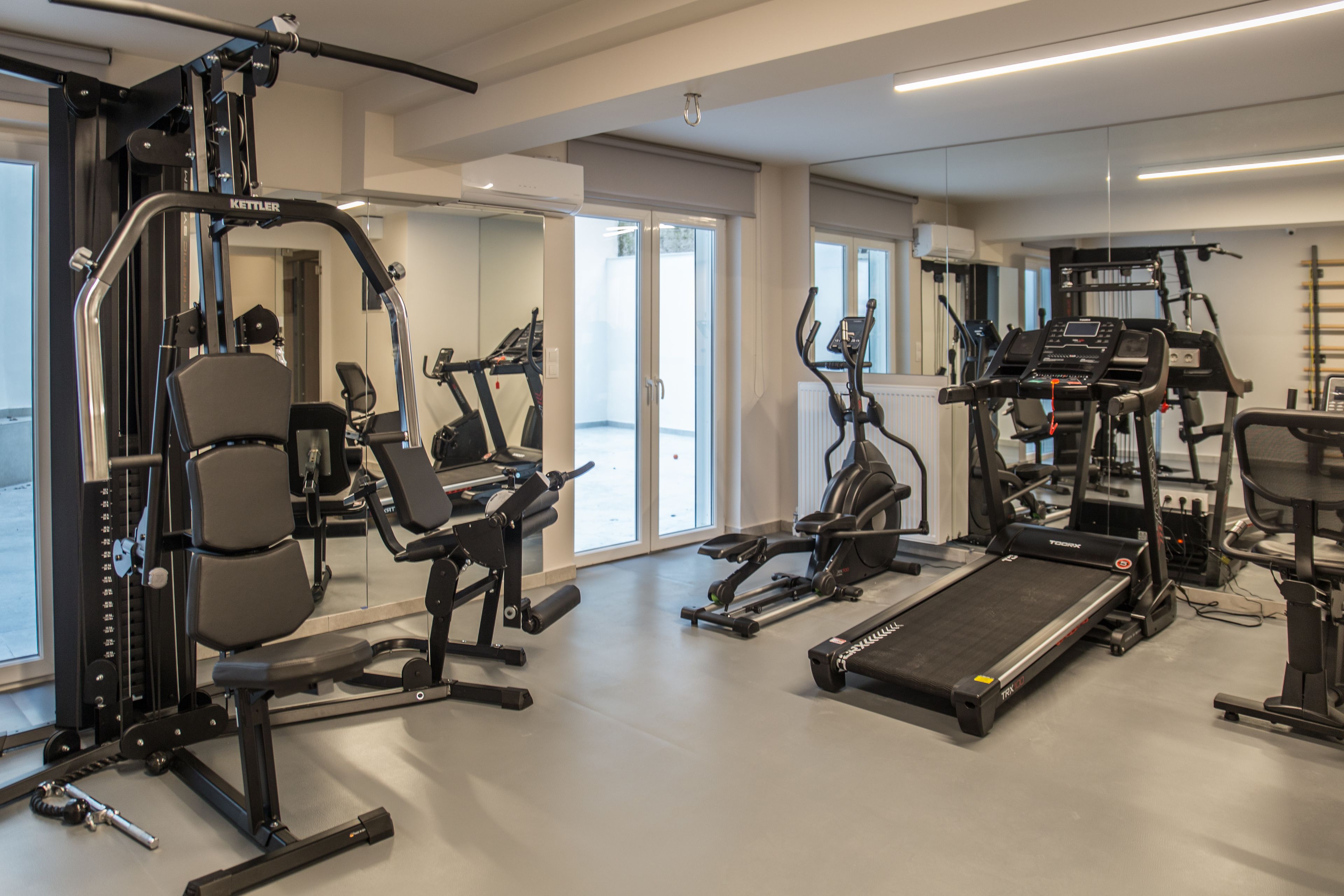 Une salle de sport équipée de divers appareils d’entraînement, notamment des tapis de course et des appareils de musculation.