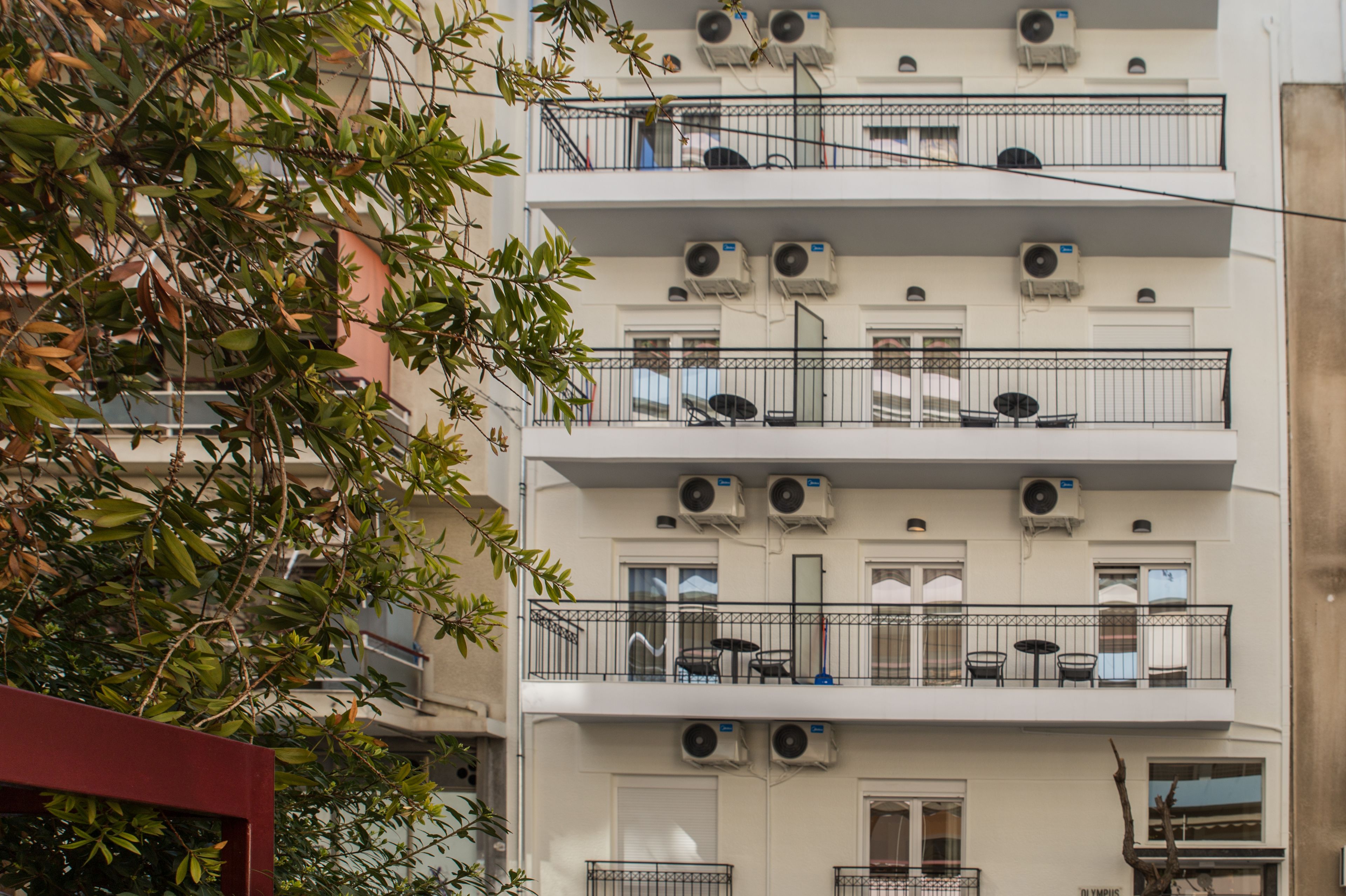 Ein mehrstöckiges Gebäude mit Balkonen, Klimaanlagen und Gartenmöbeln.