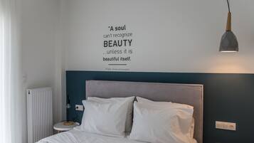 A bedroom with a bed, a bedside table, a wall-mounted light, and a quote about beauty.