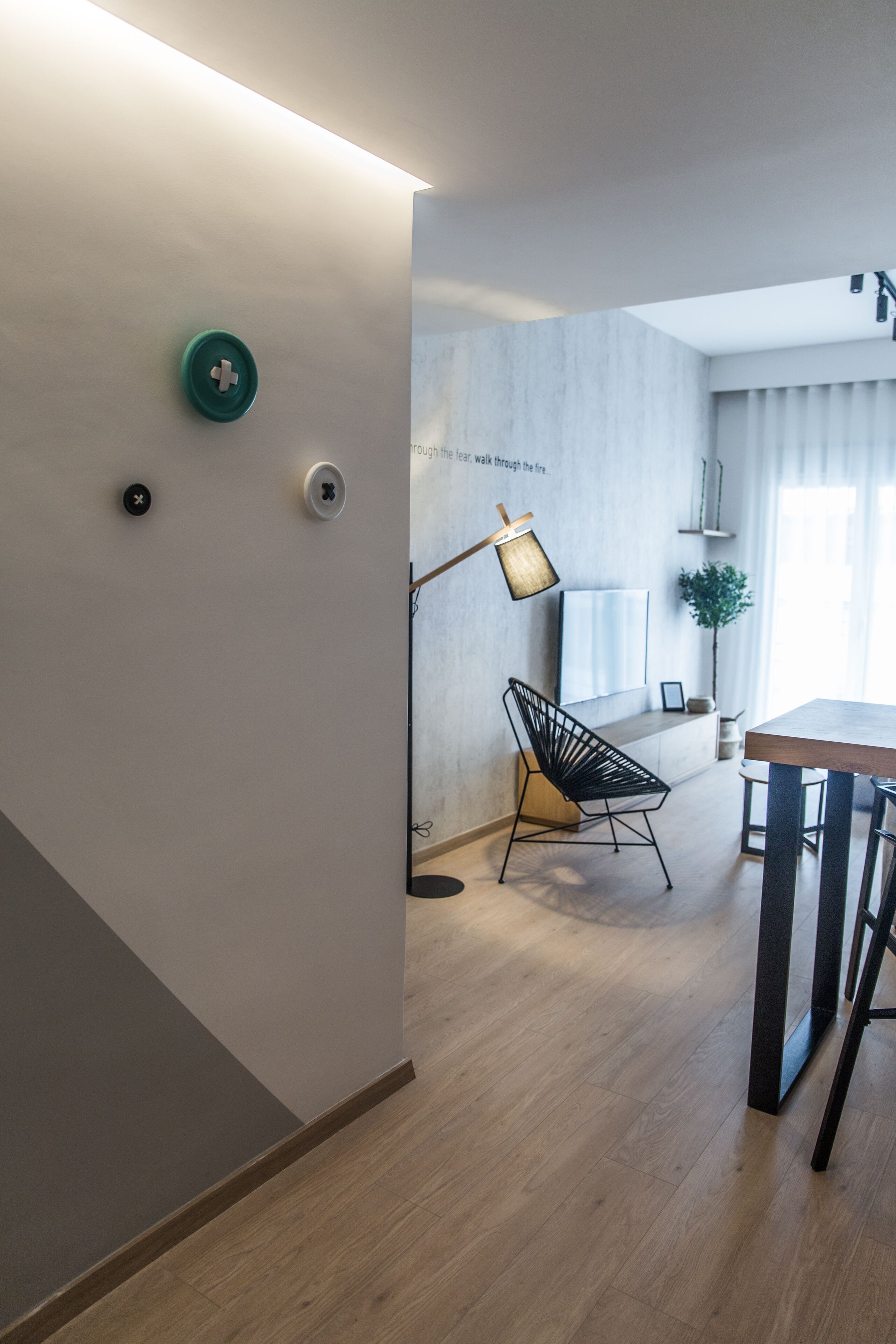 Een moderne keuken met een eethoek, met een houten vloer, een zwarte stoel, een tafel en een hanglamp.
