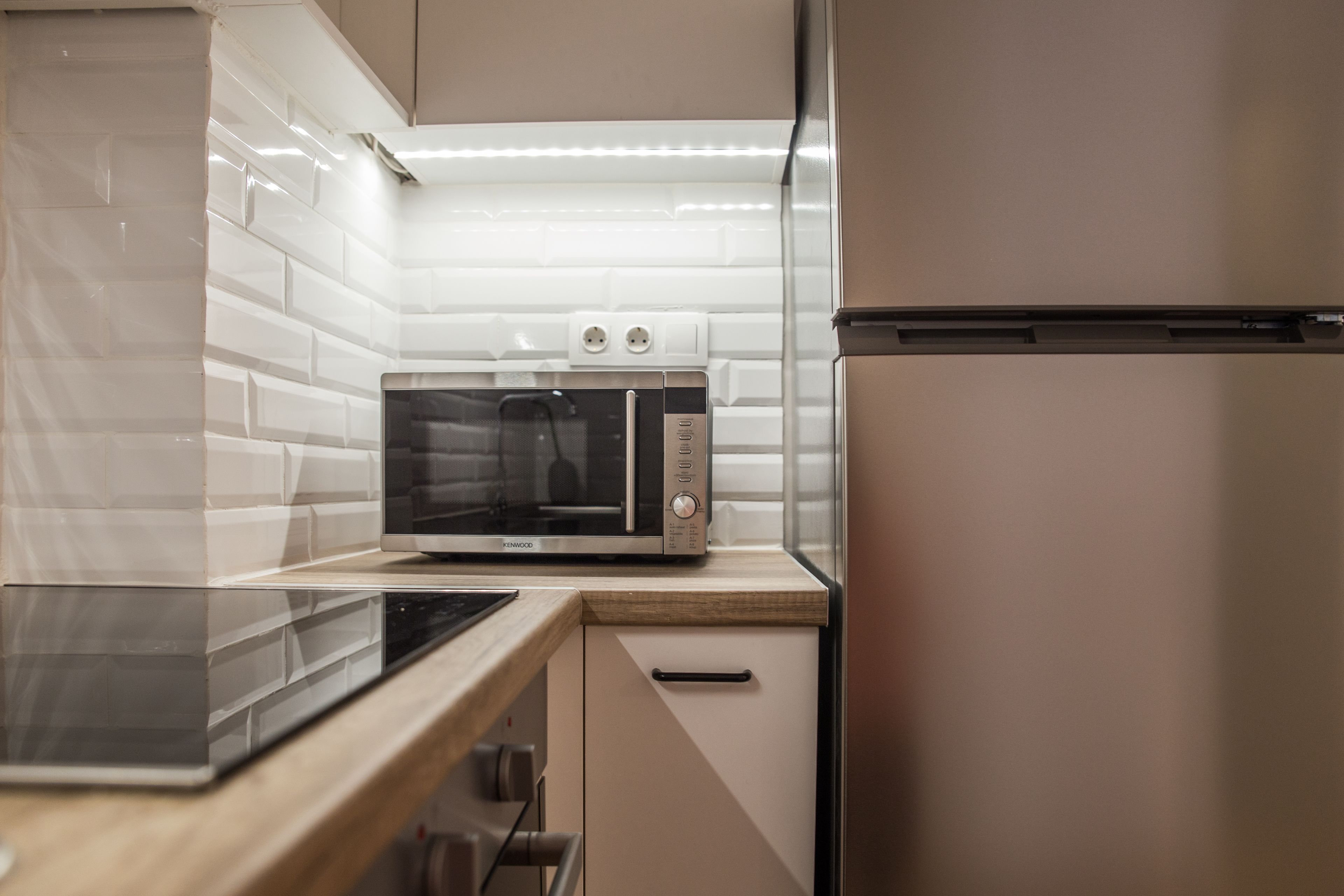 A modern kitchen with a microwave, a built-in oven, and a stainless steel refrigerator.