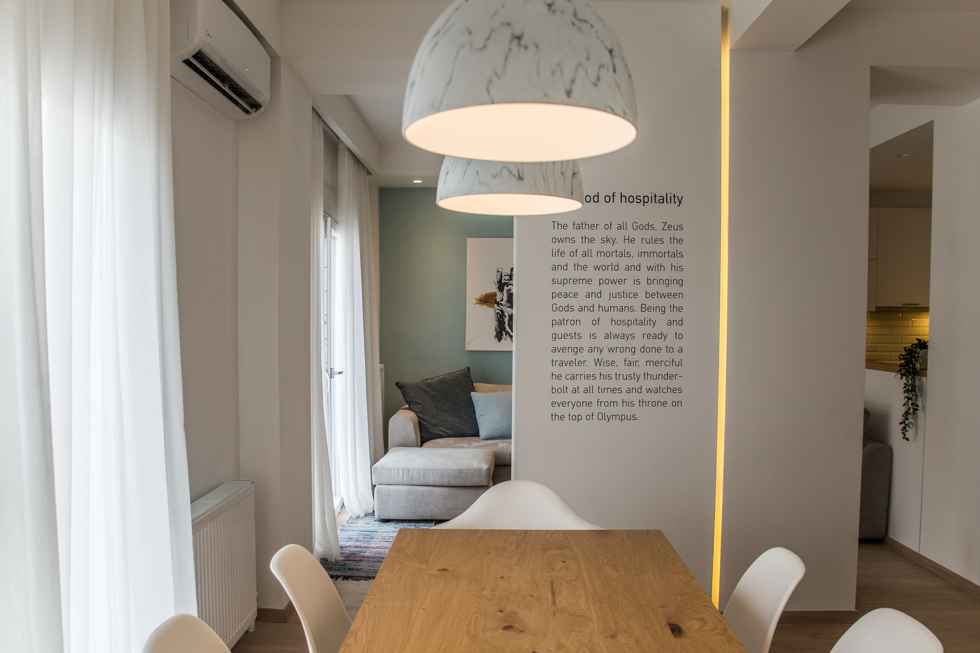 A modern dining area with a wooden table, white chairs, and a marble pendant light.