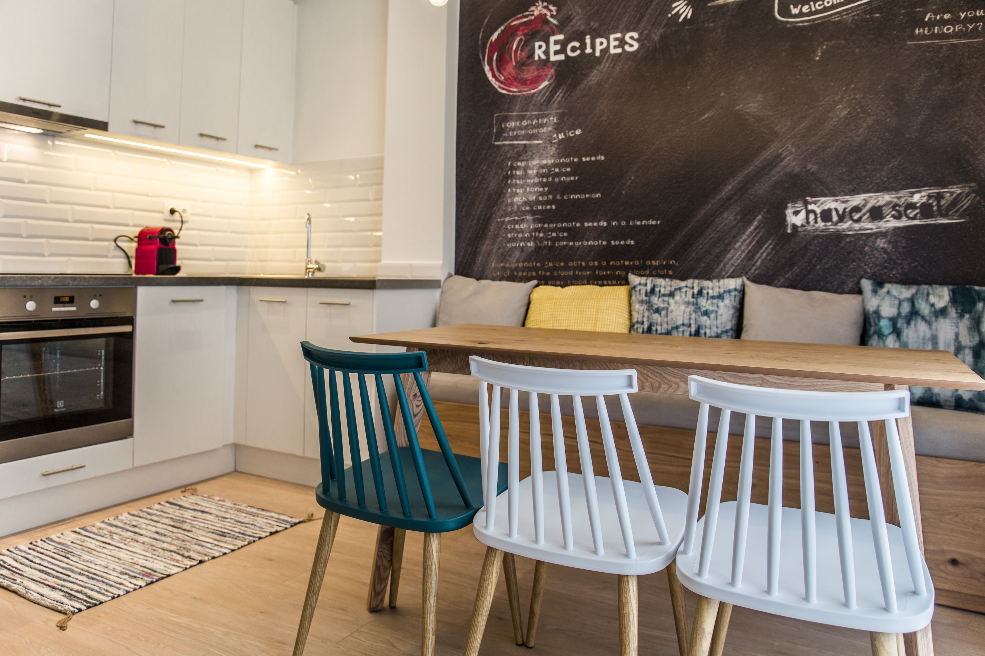 A modern kitchen with white cabinets, a wooden table, and two chairs.