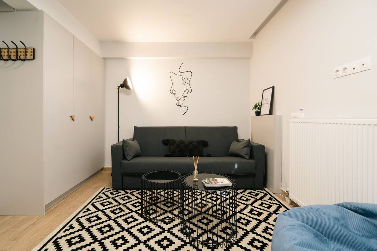 A modern living room with a dark grey sofa, a black coffee table, and a patterned rug.
