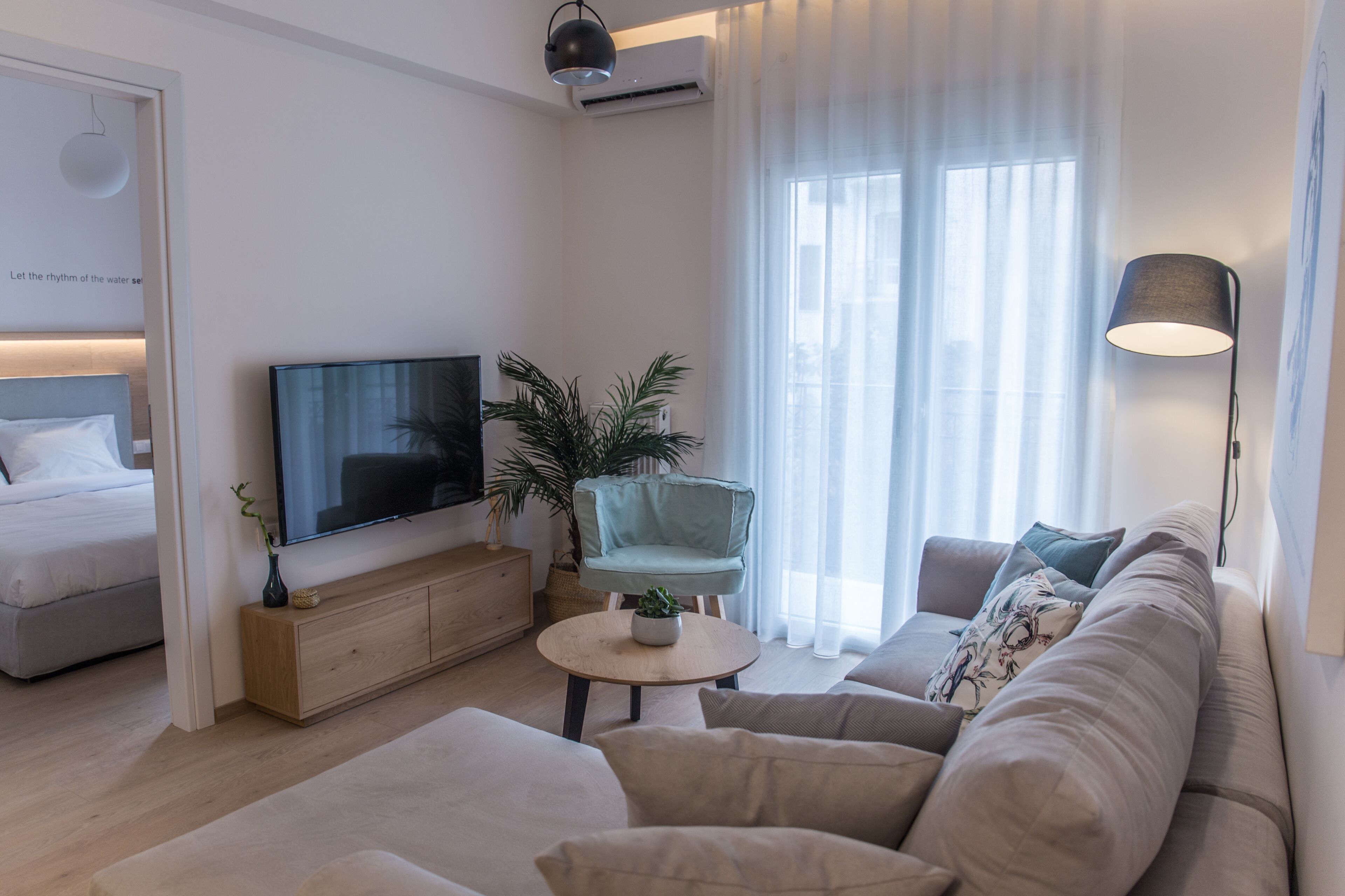 A modern living room with a sofa, a television, a small table, and a chair.