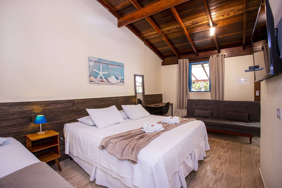 Habitación de hotel con una cama grande, un sofá, un escritorio y un televisor.