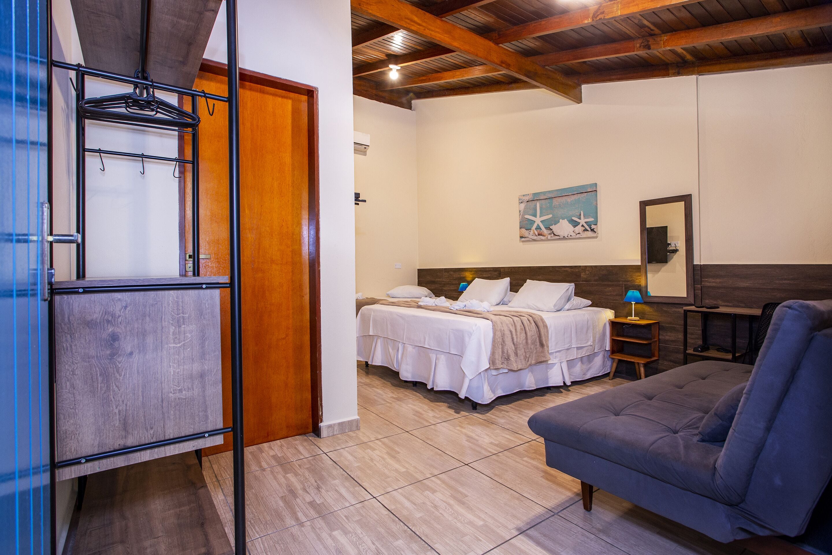 Un dormitorio con cama, sofá, techo de madera y un cuadro en la pared.
