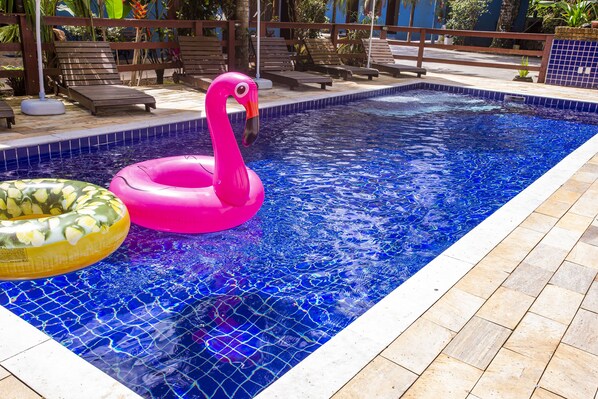 A swimming pool with a pink flamingo float and a yellow floral float. - Pousada Villa Blu Maresias (São Sebastião)