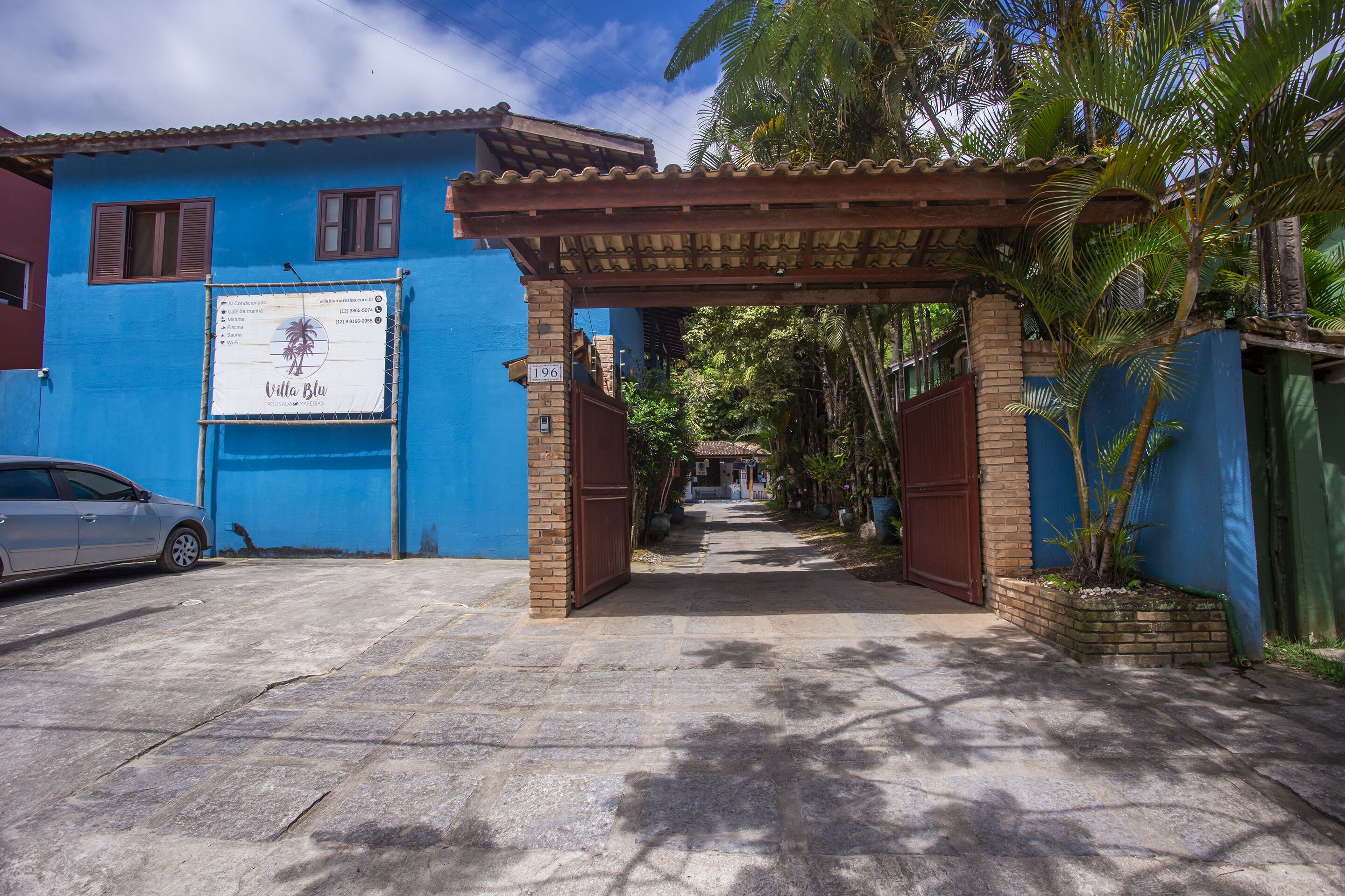 A blue building with a sign reading "Villa Blu" and a car parked in front.