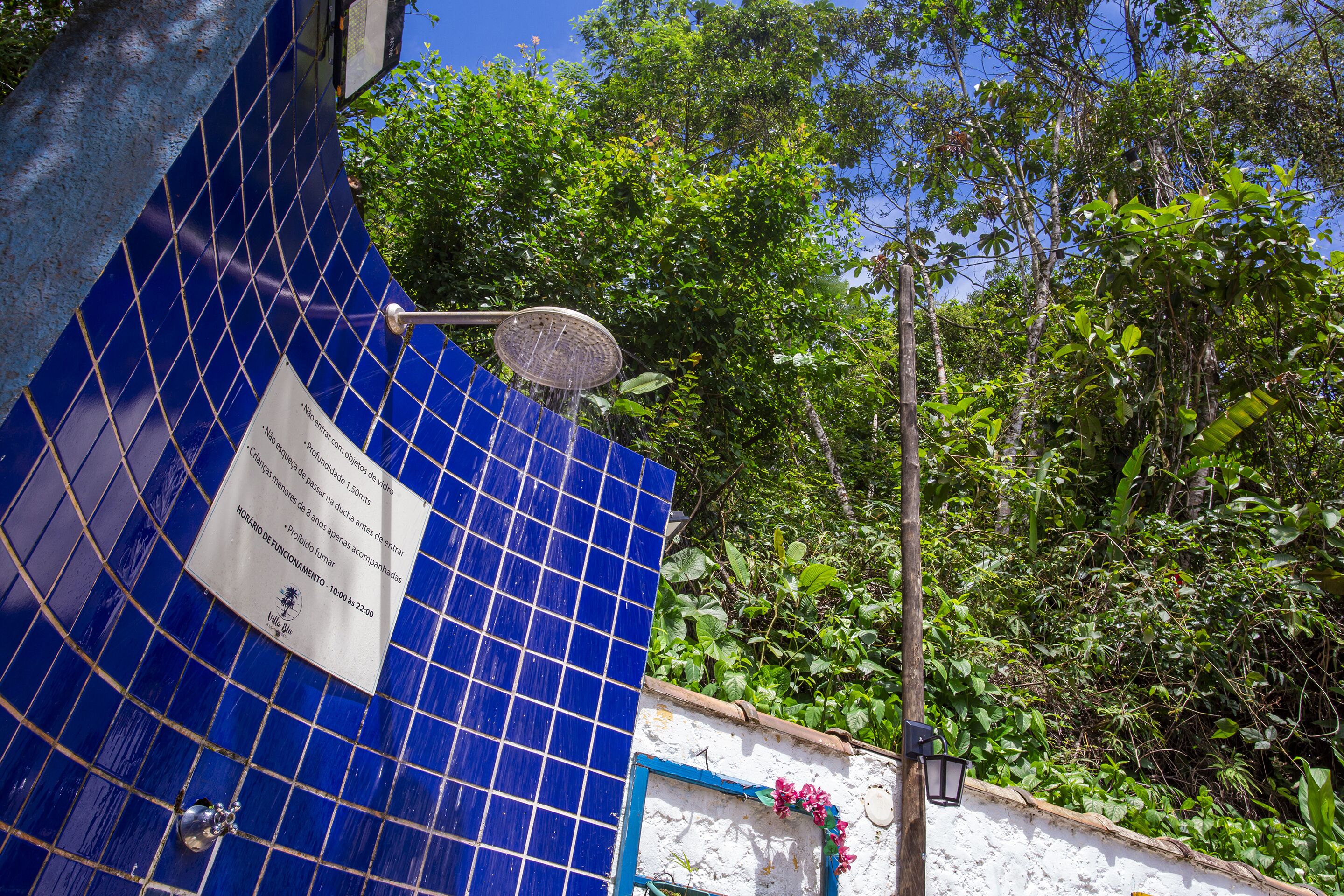 A blue tiled wall with a sign and a metal object.