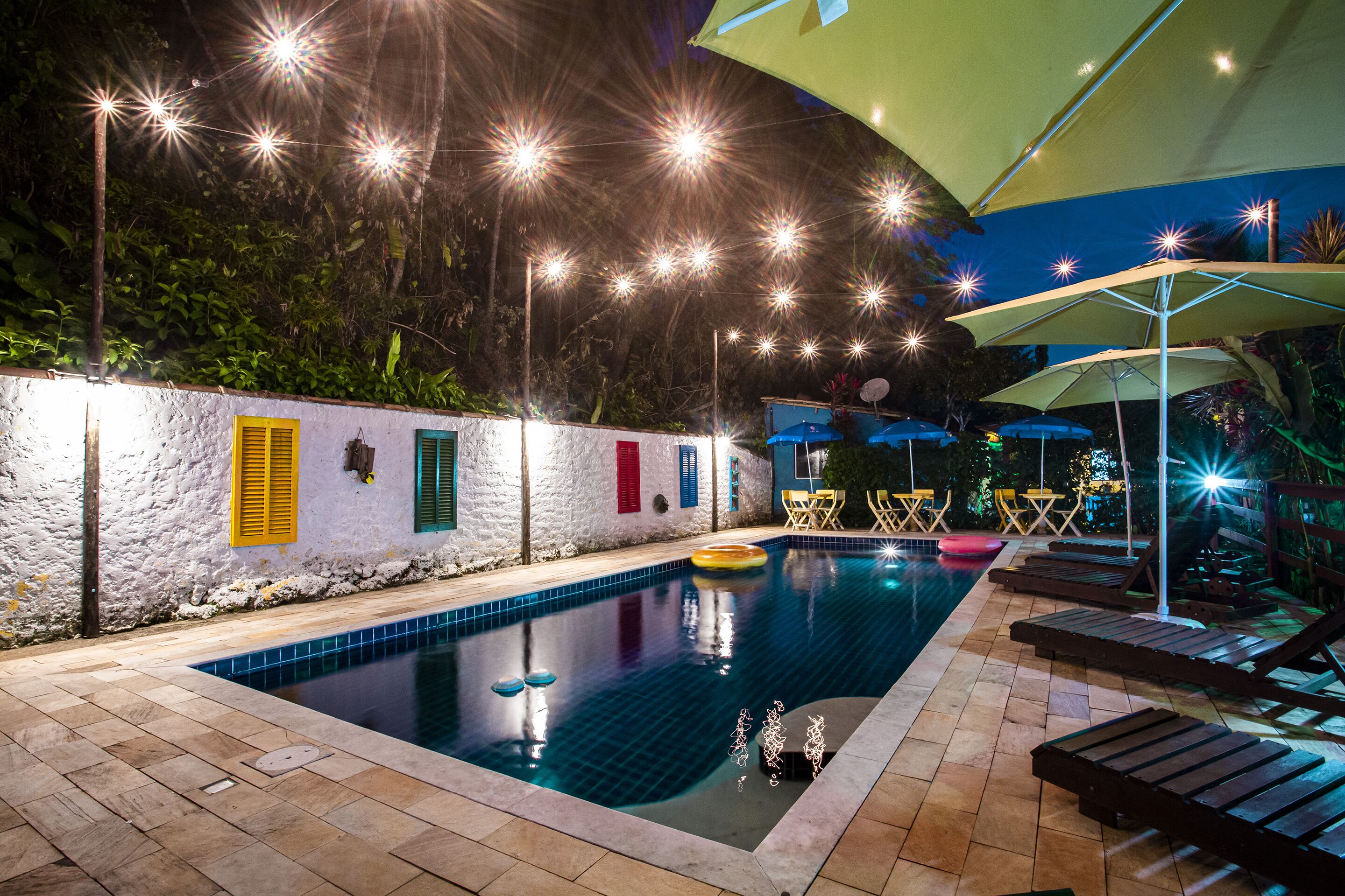 An indoor swimming pool with a tiled floor, surrounded by lounge chairs and umbrellas.