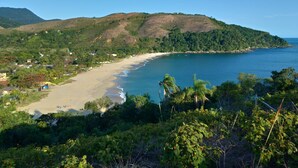 Un paysage côtier comprenant une plage, des collines et une végétation luxuriante.