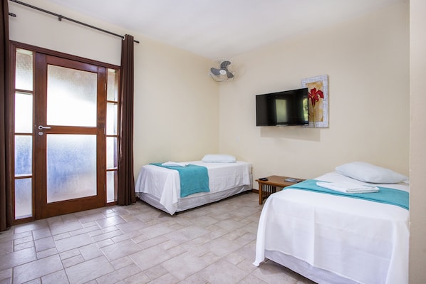 A hotel room with two beds, a TV, and a door with frosted glass panels.
