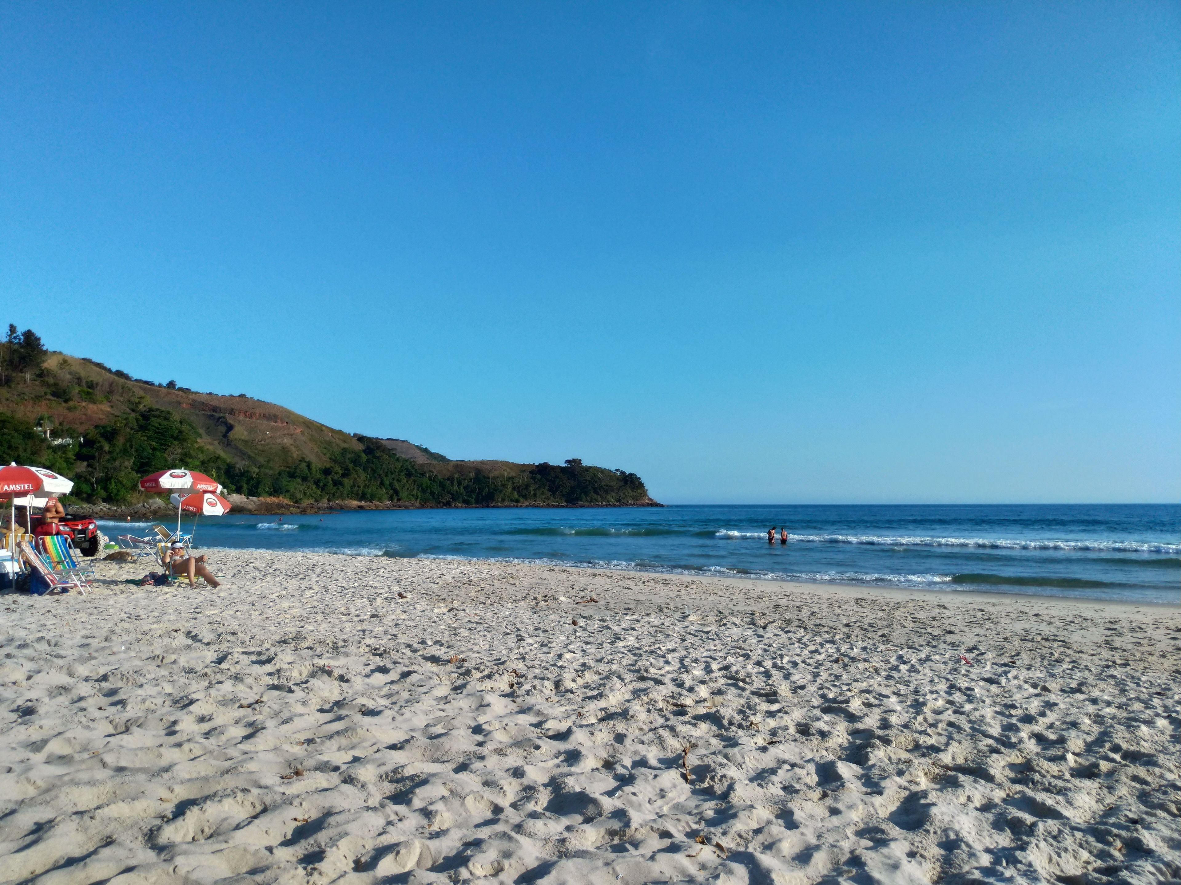 Ein Sandstrand mit Sonnenschirmen und einigen Personen.