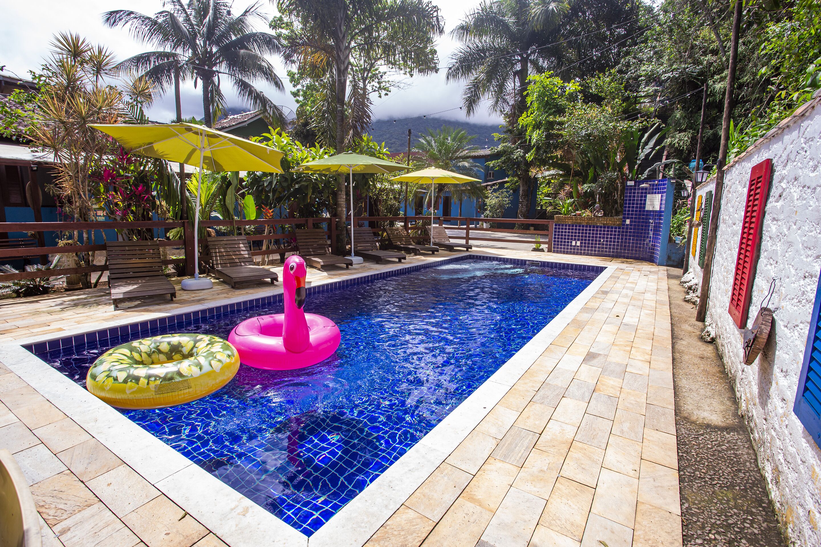 A swimming pool with two inflatable rings, surrounded by lounge chairs and umbrellas.