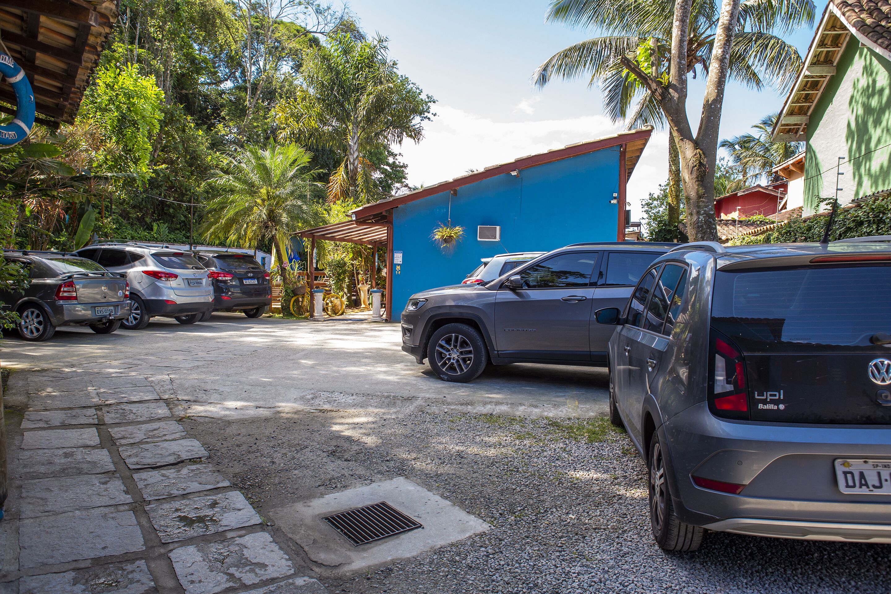 Un estacionamiento con varios coches, un edificio azul con un letrero y palmeras.