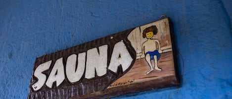 A wooden sign with the word "SAUNA" and a drawing of a person.