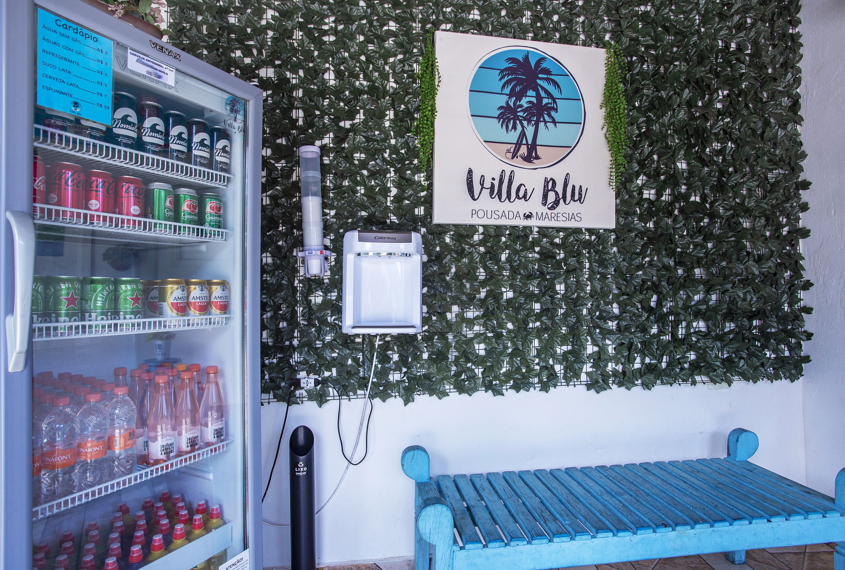 Ein Getränkeautomat, ein Schild mit der Aufschrift Villa Blu und eine blaue Bank.