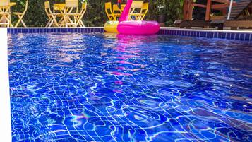 Una piscina al aire libre, sillones reclinables de piscina