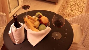 A hotel room with a bed, a dining table with fruits and wine, and a nightstand with a lamp. - Trilyali Butik Otel (Mudanya)