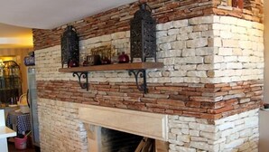 A stone fireplace with a mantel shelf and a built-in wood stove. - Trilyali Butik Otel (Mudanya)