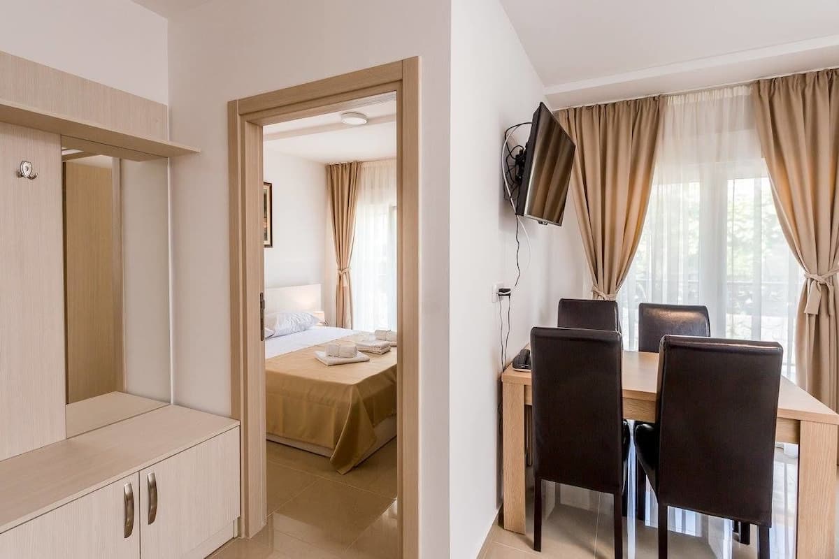 Ein Hotelzimmer mit einem Bett, einem Schreibtisch mit Stühlen, einem Fernseher und einem Kleiderschrank.