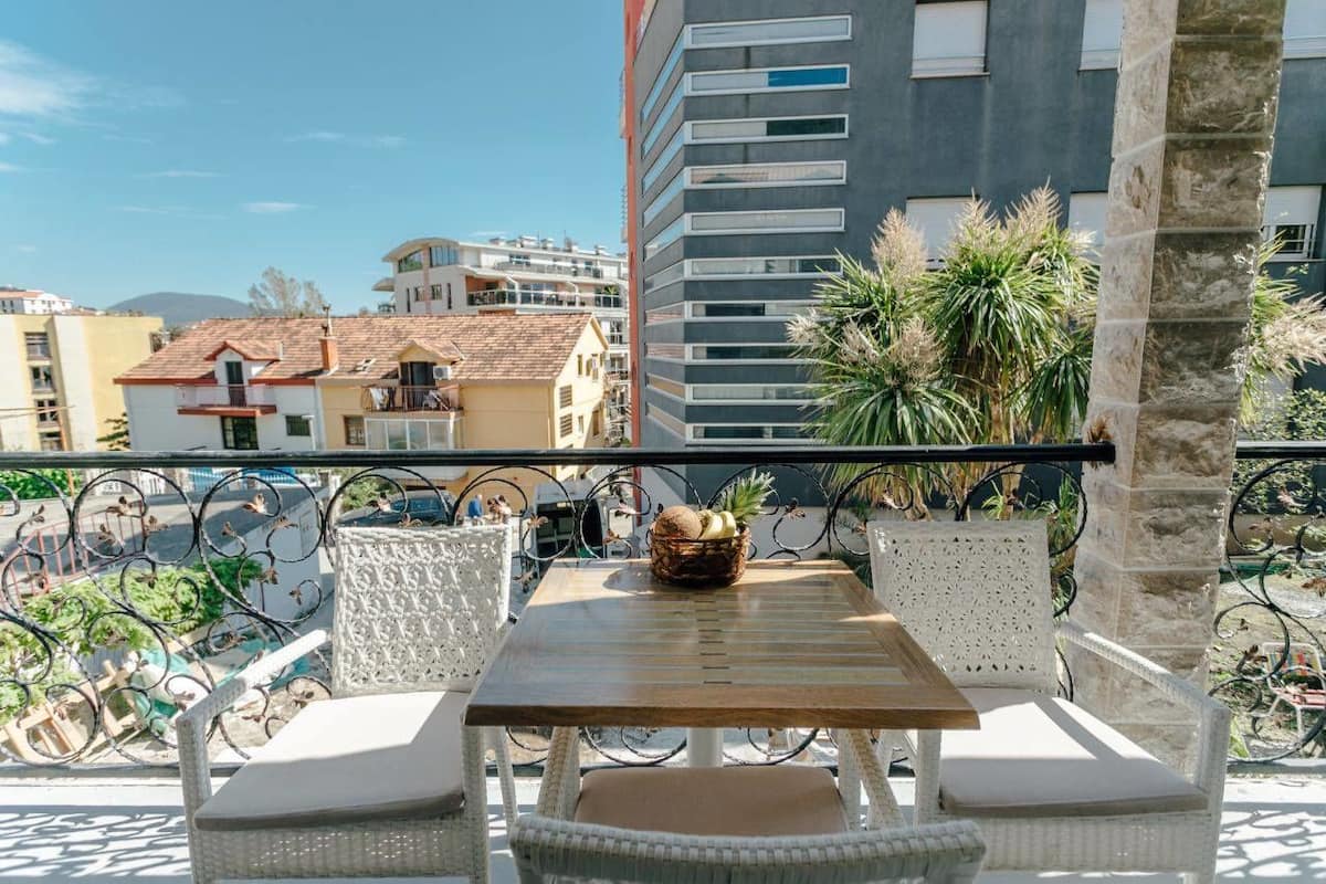 Ein Balkon mit Korbmöbeln, einem Holztisch und einer Fruchtkorb.