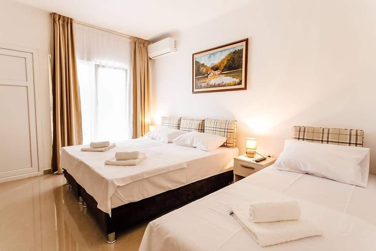 Ein Hotelzimmer mit zwei Betten, einem Bild an der Wand und einem Fenster mit Vorhängen.