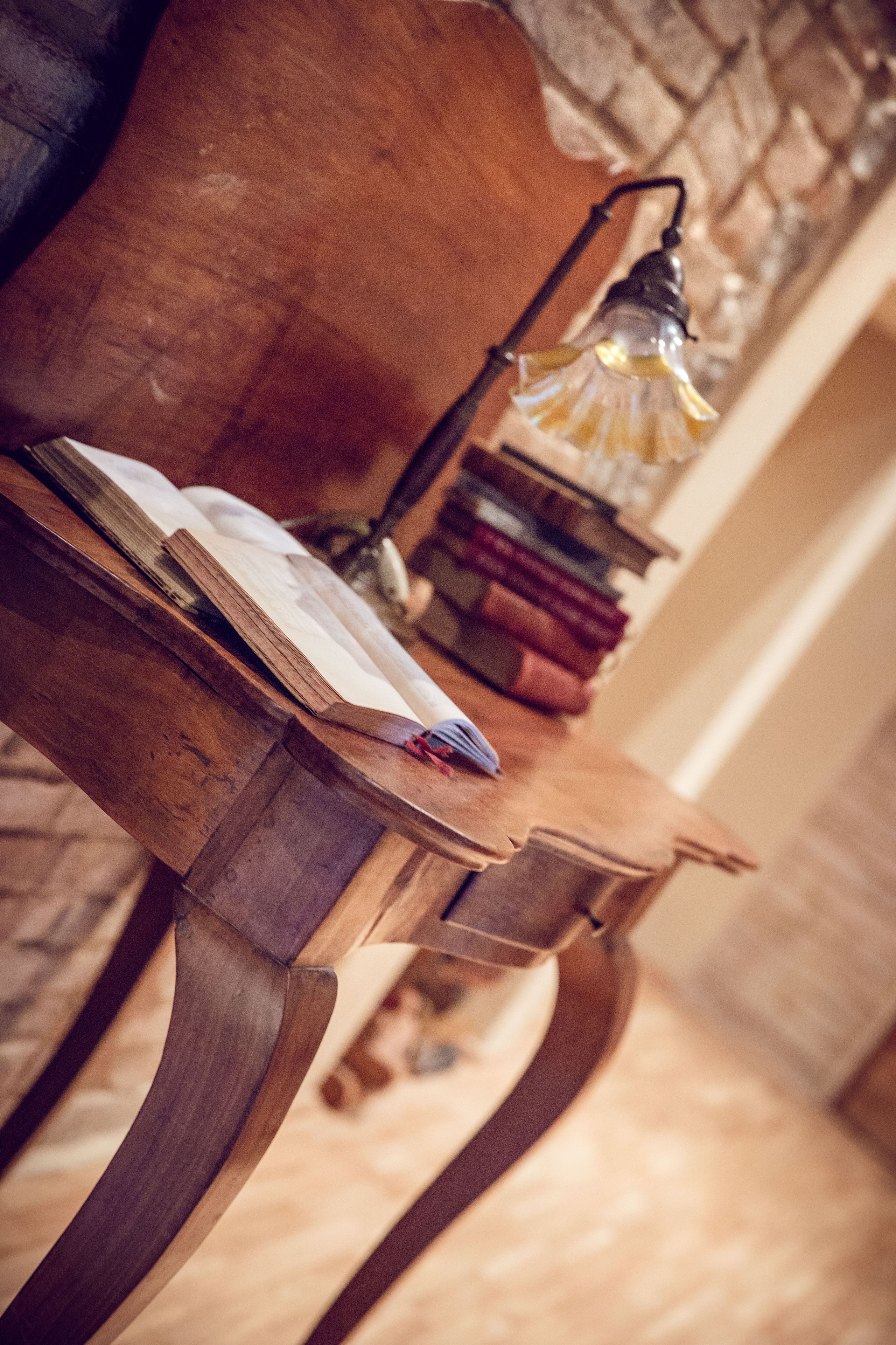 A wooden table with a book and a lamp.