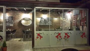 Una habitación con pared de ladrillo, un espejo redondo y una puerta de cristal con detalles florales.