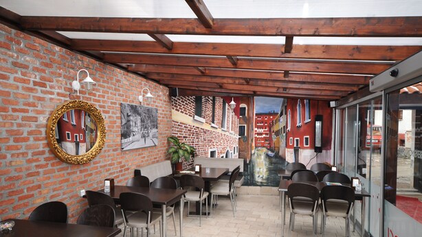 A restaurant with brick walls, wooden beams, and a canal view. - Hasirci Konaklari (Amasya)