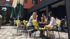 An outdoor seating area with yellow chairs and tables, a green umbrella, and a brick building in the background. - Zepter Hotel Drina Bajina Bašta, member of Zepter Hotels (Bajina Bašta)